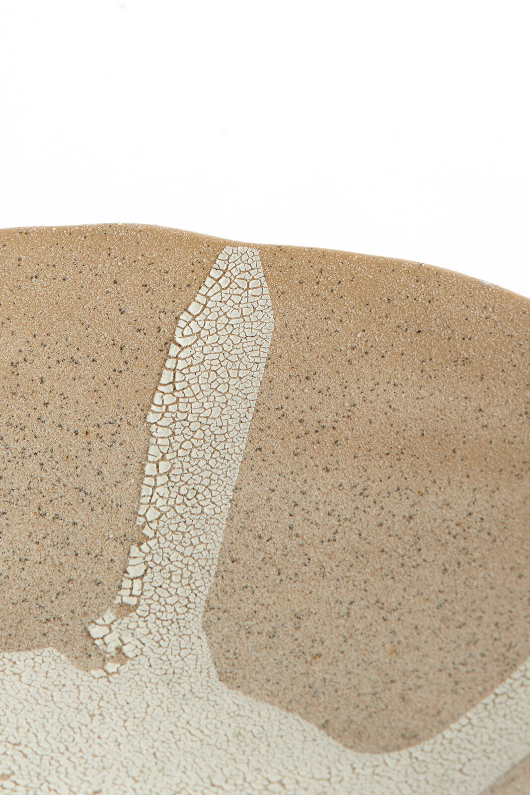 Nahaufnahme eines Ornaments mit bräunlicher, gesprenkelter Oberfläche und einem weißen, rissigen Muster. Perspektive von oben.