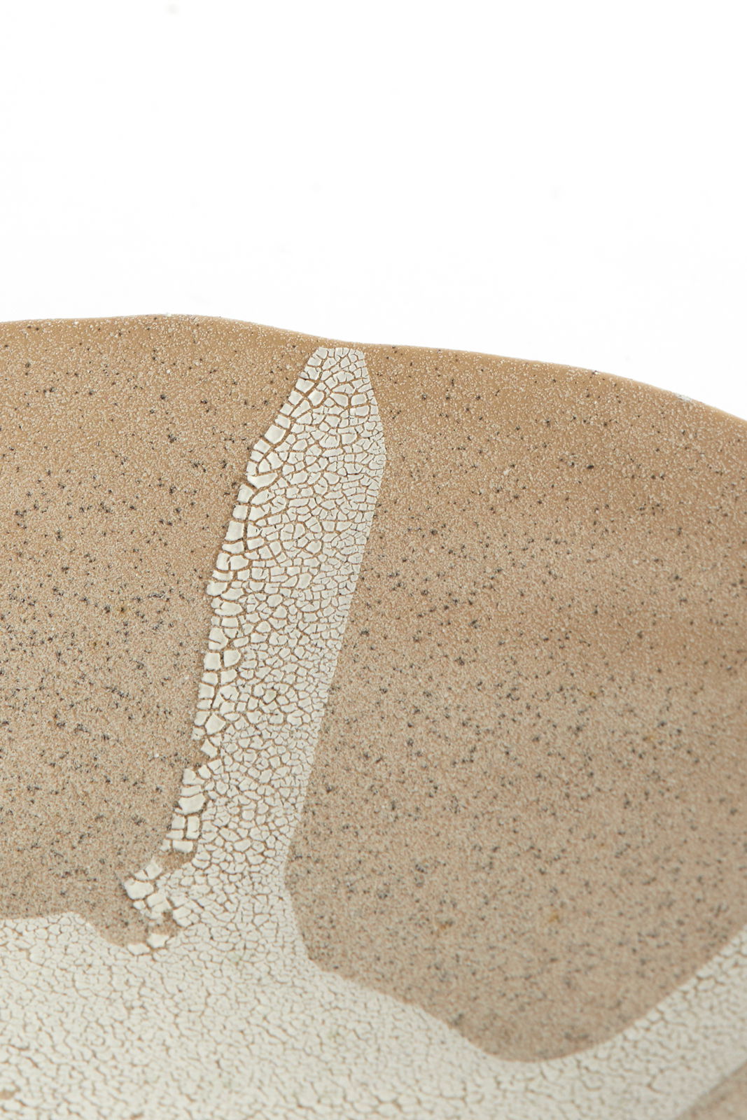 Nahaufnahme eines Ornaments mit bräunlicher, gesprenkelter Oberfläche und einem weißen, rissigen Muster. Perspektive von oben.