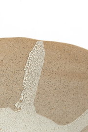 Nahaufnahme eines Ornaments mit bräunlicher, gesprenkelter Oberfläche und einem weißen, rissigen Muster. Perspektive von oben.