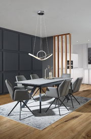 Moderner Esstisch mit grauer Tischplatte und schwarzen Beinen, umgeben von sechs grauen Stühlen auf einem Teppich, aus der Perspektive des Raumes betrachtet.