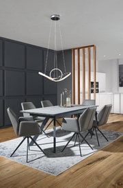 Moderner Esstisch mit grauer Tischplatte und schwarzen Beinen, umgeben von sechs grauen Stühlen auf einem Teppich, aus der Perspektive des Raumes betrachtet.
