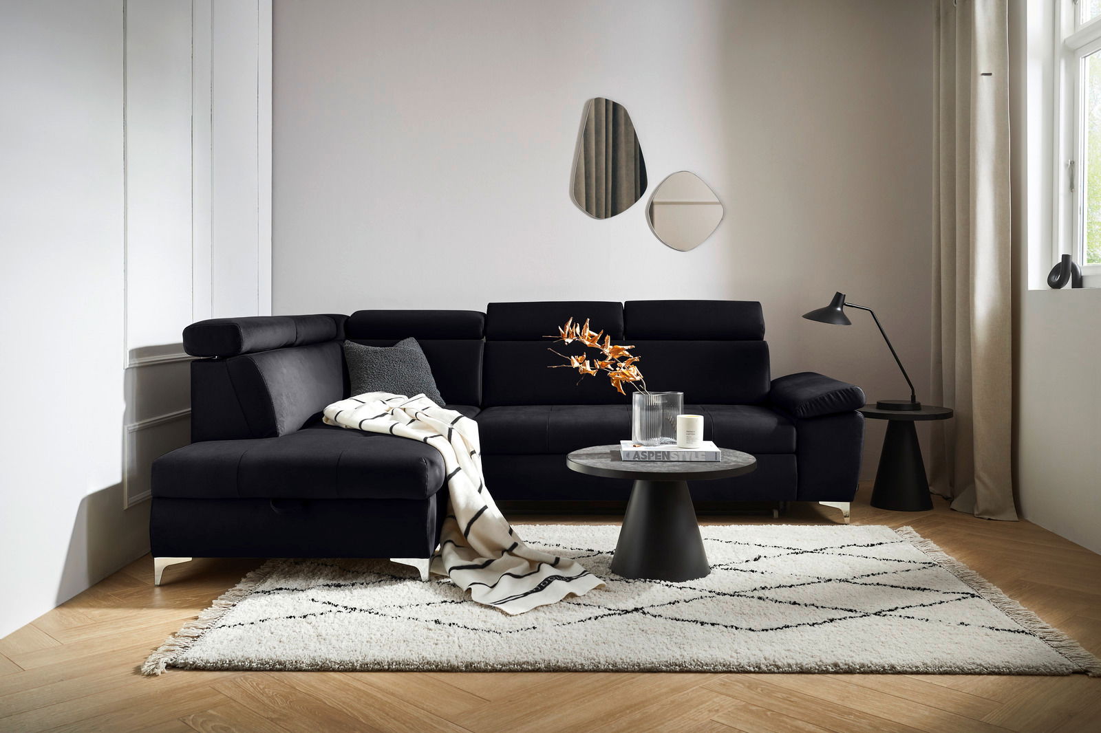 Schwarze Rundecke (L) in einem modernen Wohnzimmer, von vorne betrachtet, mit einem Beistelltisch und Dekorationen.