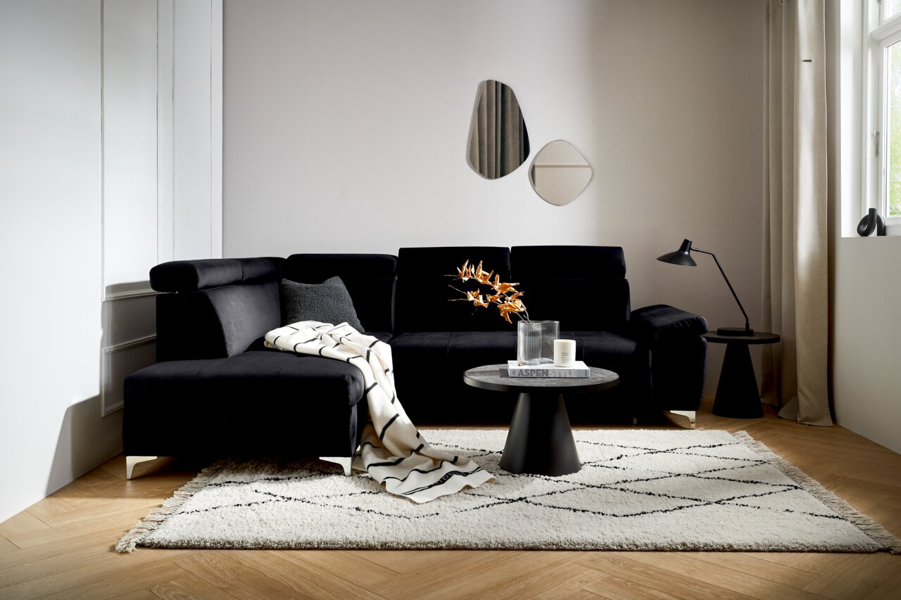Zwarte hoekbank (L) in een moderne woonkamer, gezien vanaf de voorkant, met een bijzettafeltje en decoraties.