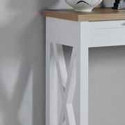 Detailansicht einer weißen Konsole mit Holzplatte und dekorativem X-Muster an der Seite.