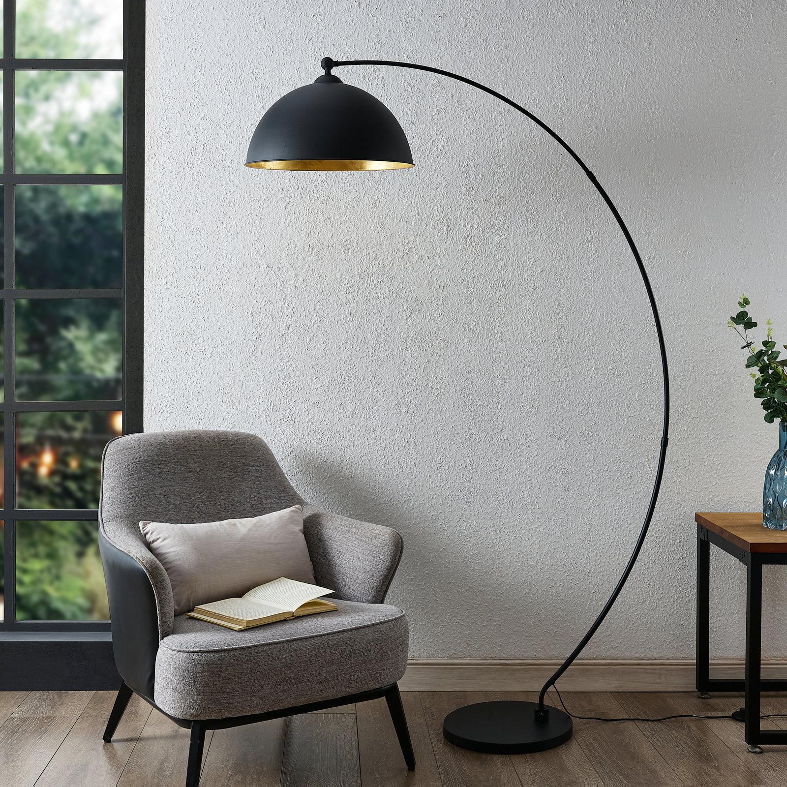 Moderne Stehleuchte mit gebogenem Arm und schwarzem Lampenschirm, seitliche Perspektive.