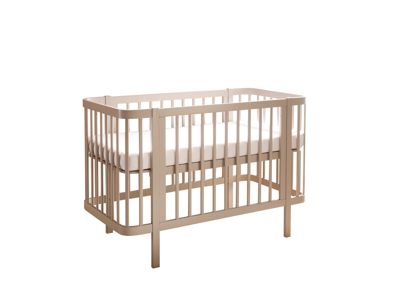 Beiges Babybett aus Holz mit Gitterseiten und weißer Matratze, freigestellt auf weißem Hintergrund, Ansicht schräg von vorne.