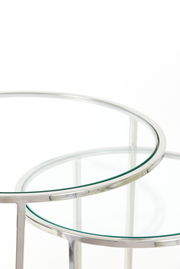 Nahaufnahme von zwei runden Beistelltischen mit Glasplatten und silbernem Metallrahmen, perspektivisch von oben fotografiert.