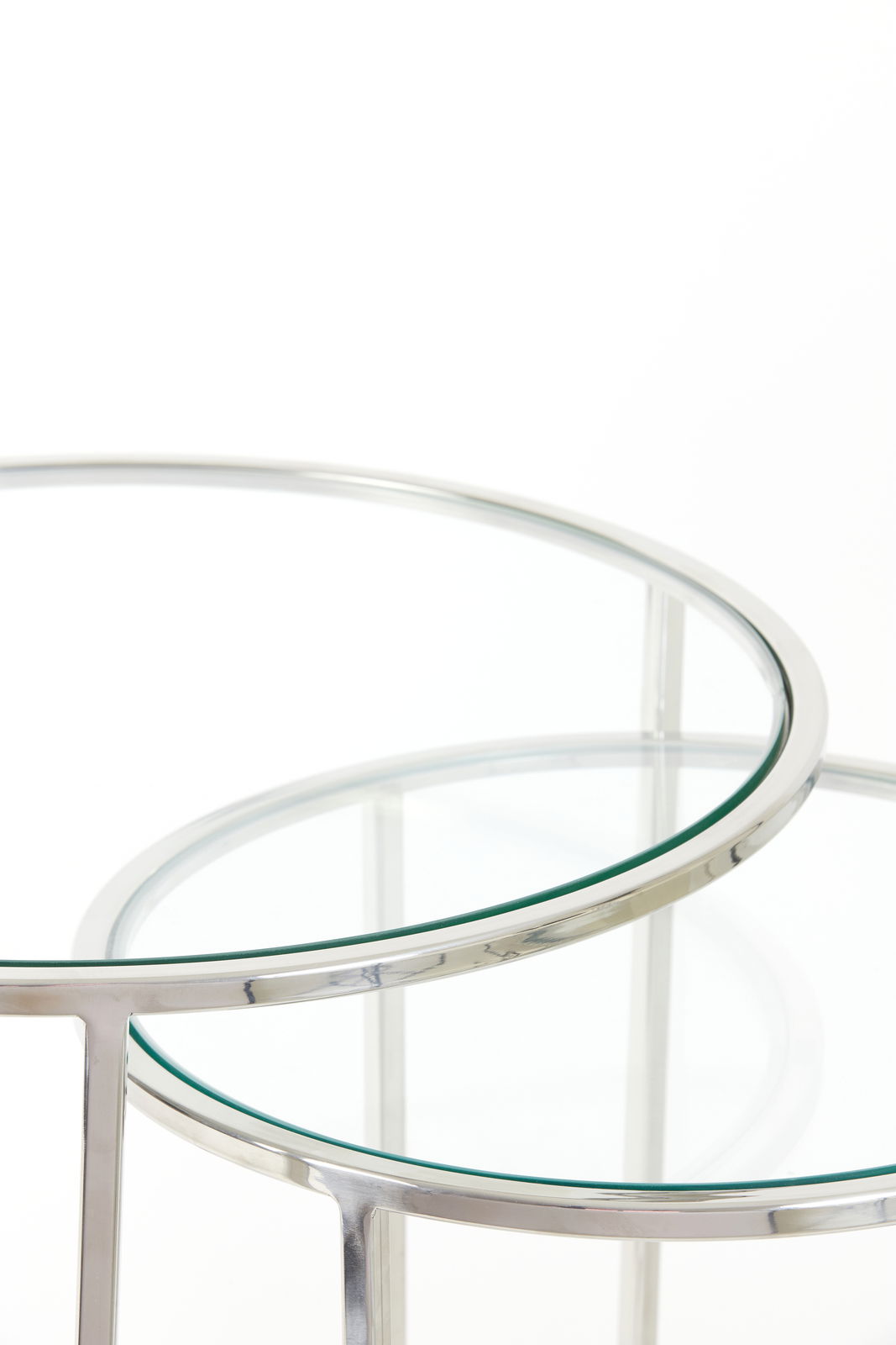 Nahaufnahme von zwei runden Beistelltischen mit Glasplatten und silbernem Metallrahmen, perspektivisch von oben fotografiert.