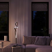Moderne LED-Stehleuchte mit geschwungenem Design in einem stilvollen Wohnzimmer, seitliche Perspektive.