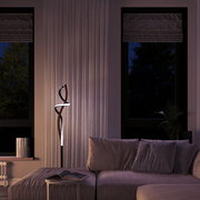Moderne LED-Stehleuchte mit geschwungenem Design in einem stilvollen Wohnzimmer, seitliche Perspektive.