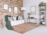 Designer Teppich in einem modernen Wohnzimmer mit Backsteinwand, Sofa und Dekorationen, aus der Perspektive von vorne rechts.