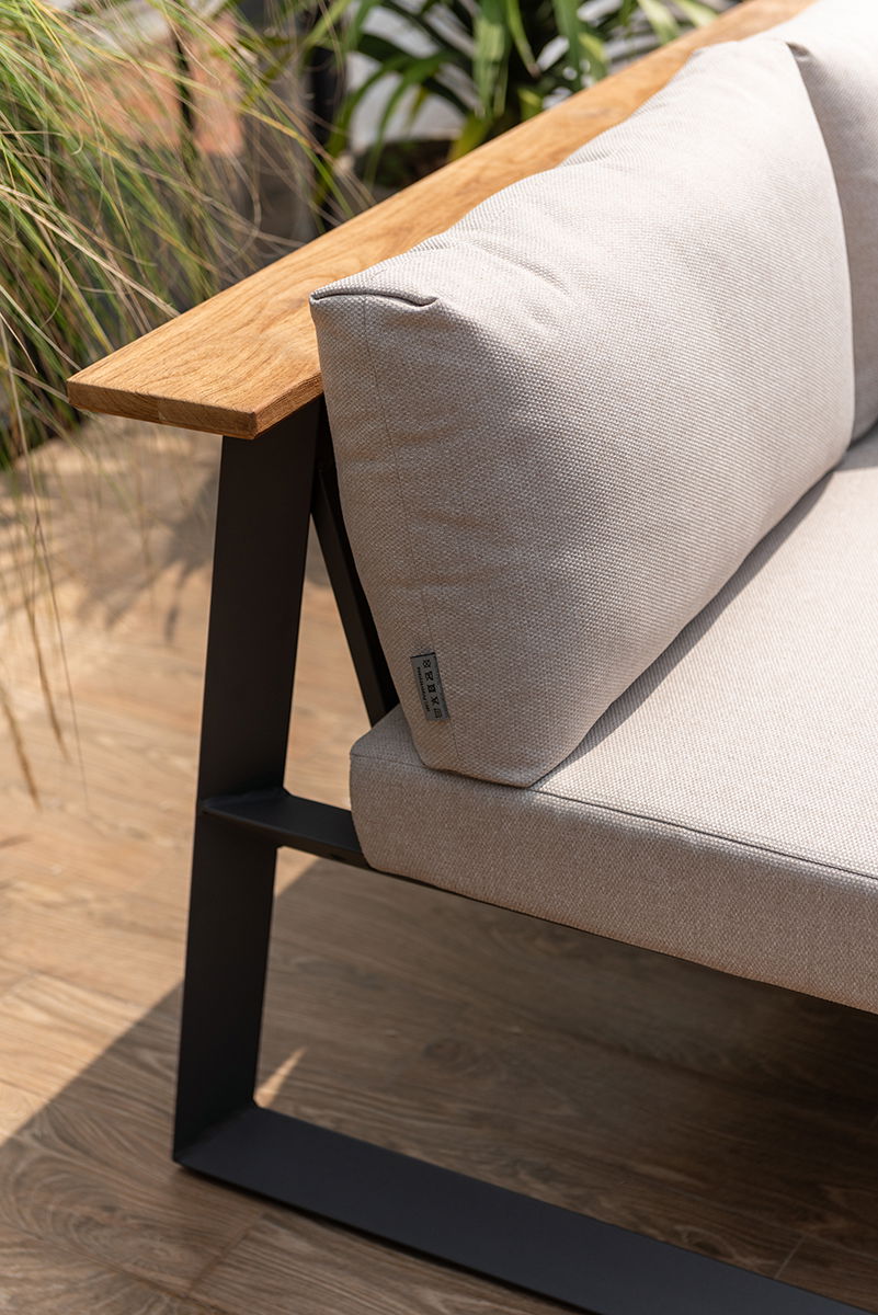 Nahaufnahme einer modernen Sitzbank mit Holzarmlehne und beigem Kissen, seitliche Perspektive.