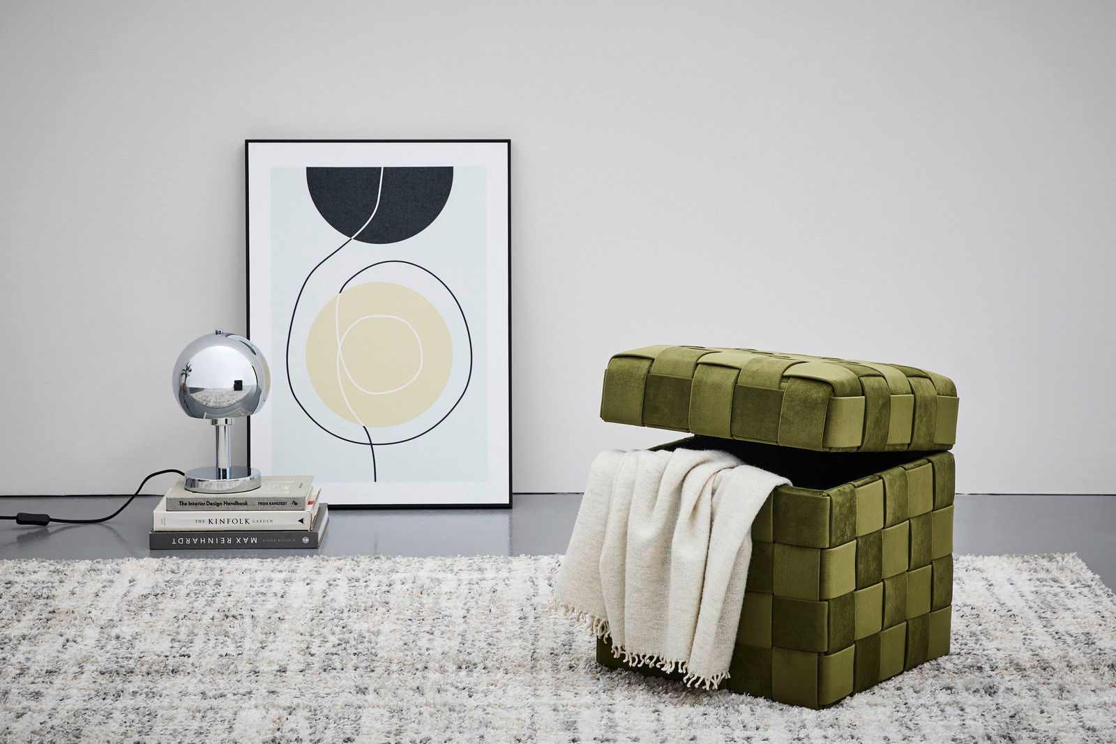 Grüner Hocker mit Stauraum, geöffnet, mit einer Decke darin, seitliche Perspektive