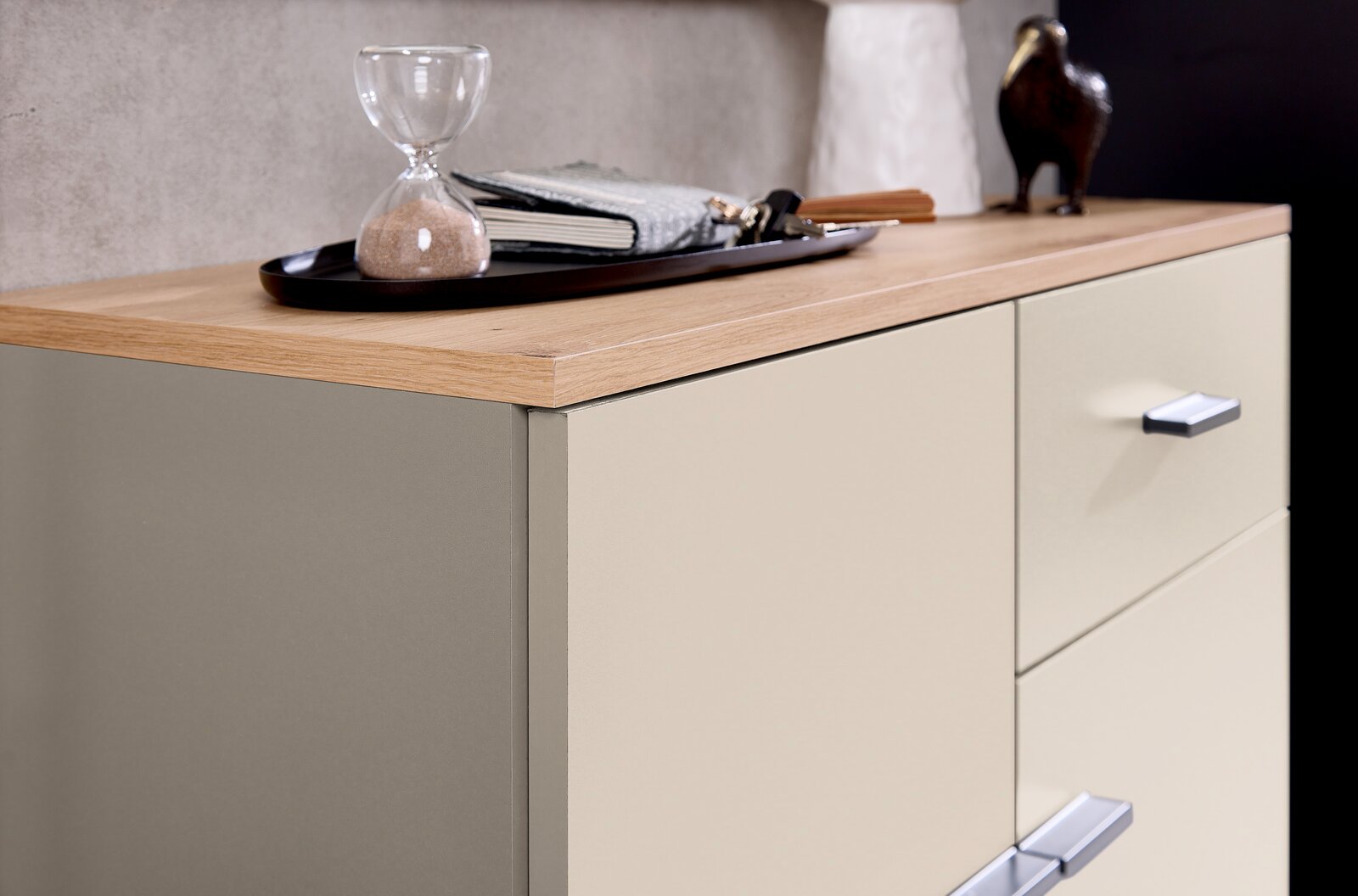 Nahaufnahme einer Kompaktgarderobe mit Holzoberfläche, dekoriert mit einer Sanduhr und einem Tablett. Perspektive von schräg oben.