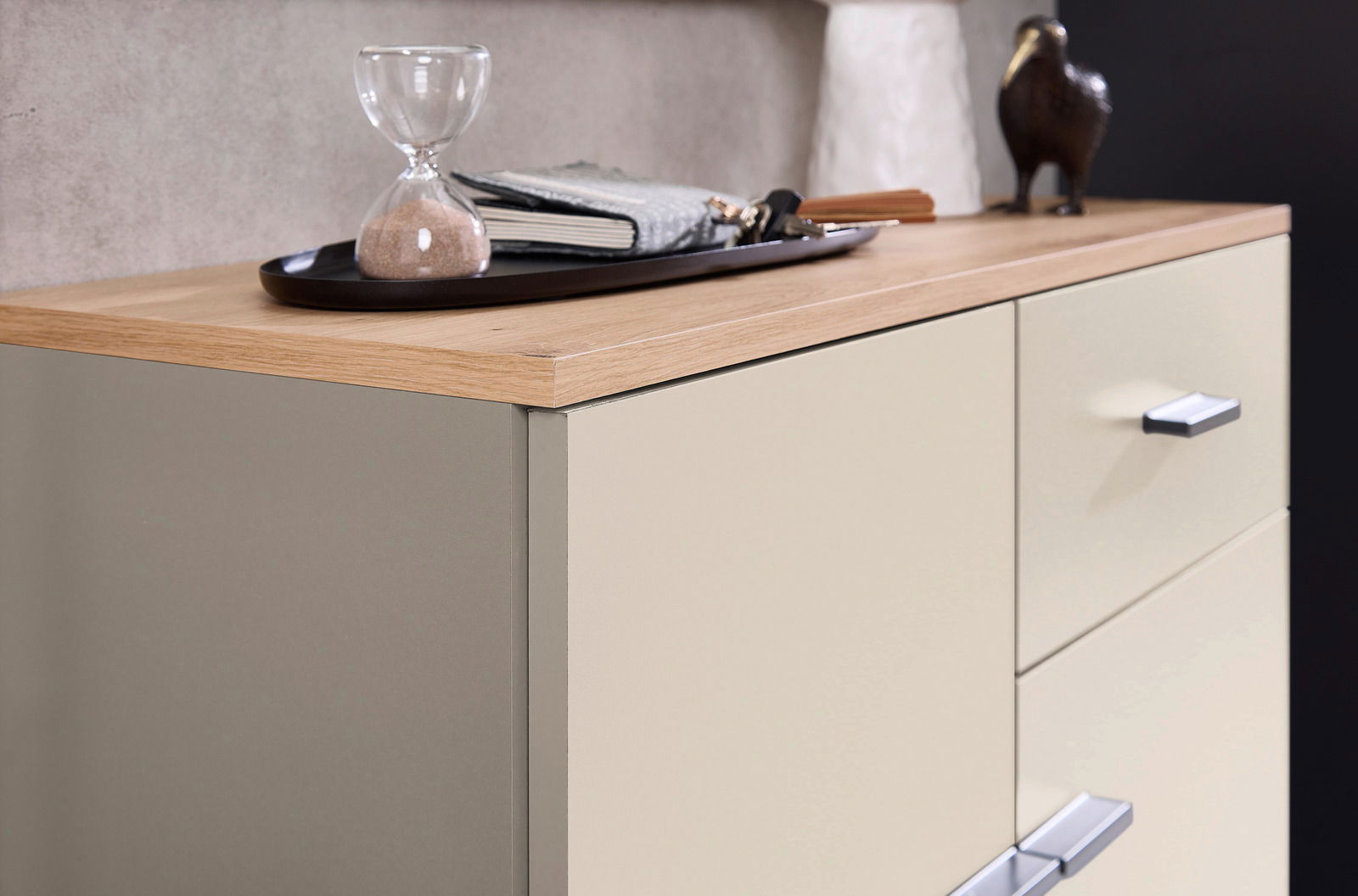 Nahaufnahme einer Kompaktgarderobe mit Holzoberfläche, dekoriert mit einer Sanduhr und einem Tablett. Perspektive von schräg oben.