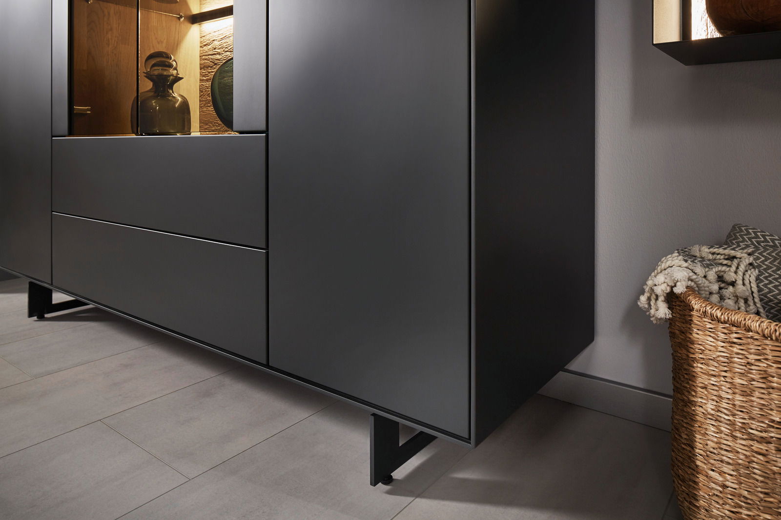 Nahaufnahme eines modernen, schwarzen Highboards mit Glasvitrine, seitliche Perspektive.