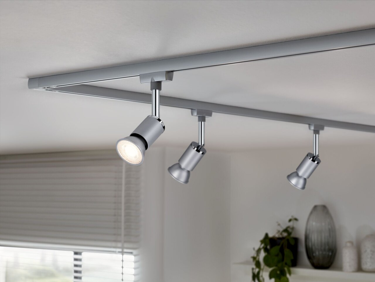 Dreifache LED-Schienenleuchte von Paulmann, montiert an der Decke, mit modernem Design in silberner Farbe, seitliche Perspektive.