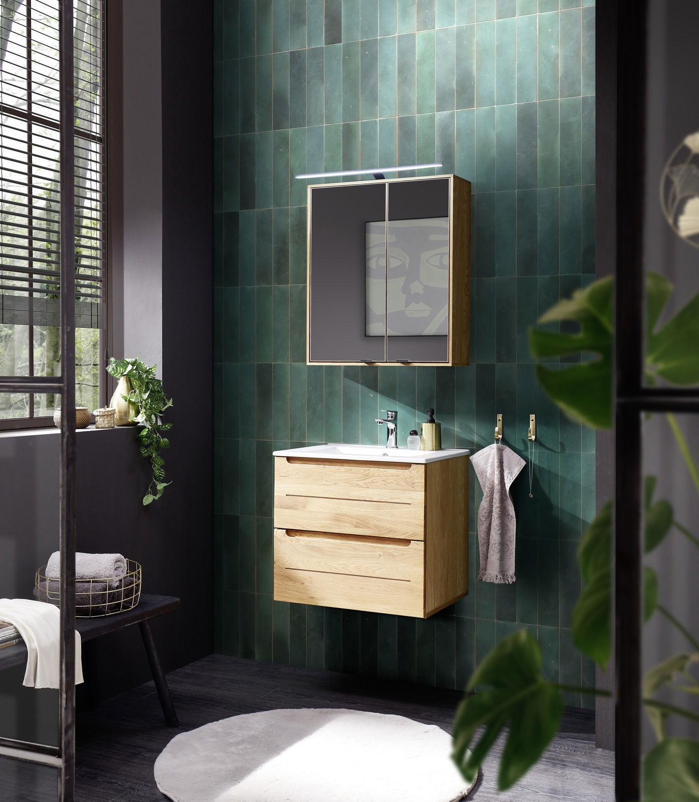 Moderner Keramikwaschtisch mit Holzunterschrank, frontal in einem stilvoll eingerichteten Badezimmer mit grünen Wandfliesen und natürlichem Licht.