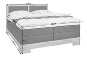 Boxspringbett in seitlicher Perspektive mit grauem Stoffbezug, Holzfüßen und Maßen 180x200 cm
