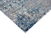 Designer Teppich mit blau-grauem Muster, perspektivisch von der Ecke aufgenommen