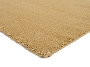 Beige Uni-Teppich in Nahaufnahme, perspektivisch von der Seite fotografiert, zeigt die weiche Textur und den dichten Flor.