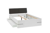Weißes Bettgestell mit schwarzem Kopfteil und Schubladen, seitliche Perspektive