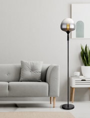 Moderne staande lamp met rookgrijs glas in een stijlvolle woonkamer, gezien vanaf de zijkant.
