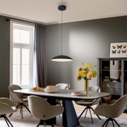 Schwarze, flache Pendelleuchte mit breitem, rundem Schirm und warmem Licht über einem Esstisch im modernen Esszimmer, Perspektive: leicht von unten in die Raumtiefe (Frontansicht).