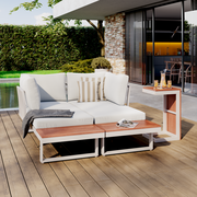 Moderne Gartenlounge mit weißem Polster und Holztisch, seitliche Perspektive, auf einer Terrasse mit Blick auf den Garten.