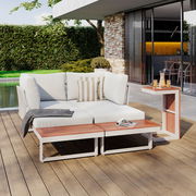 Moderne Gartenlounge mit weißem Polster und Holztisch, seitliche Perspektive, auf einer Terrasse mit Blick auf den Garten.