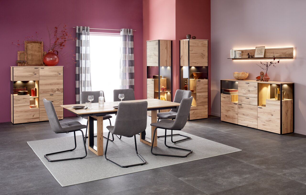 Moderne woonkamermeubelcombinatie met houtlook, bestaande uit vitrinekasten, een dressoir en een eettafel met stoelen, in een stijlvol ingerichte ruimte met paarse muren. Perspectief: vooraanzicht.