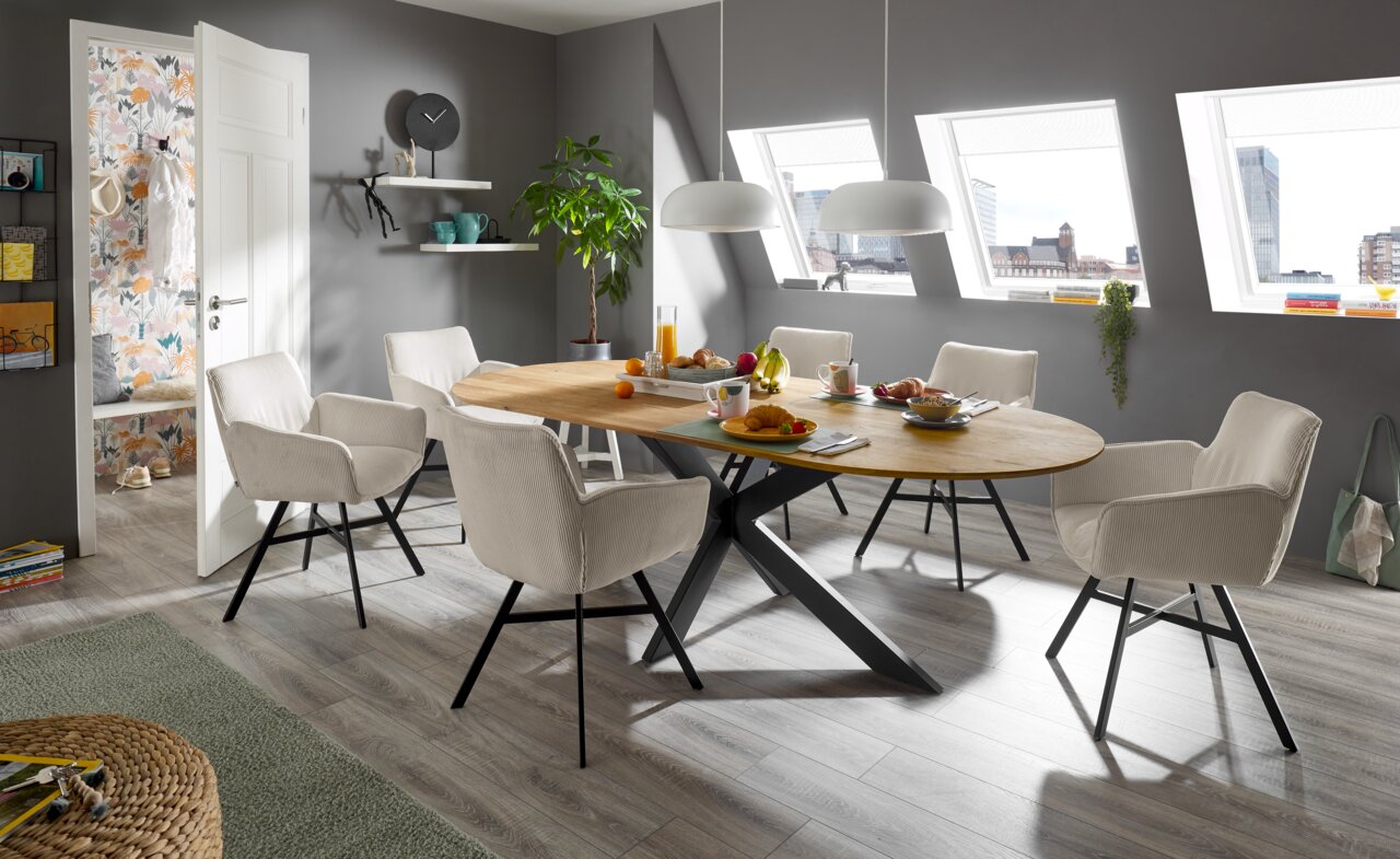 Set one by Musterring Fauteuil SET ONE FRISCO Eetkamer met moderne stoelen met armleuningen uit de FRISCO-serie van Musterring rond een ovale houten tafel, zijaanzicht.