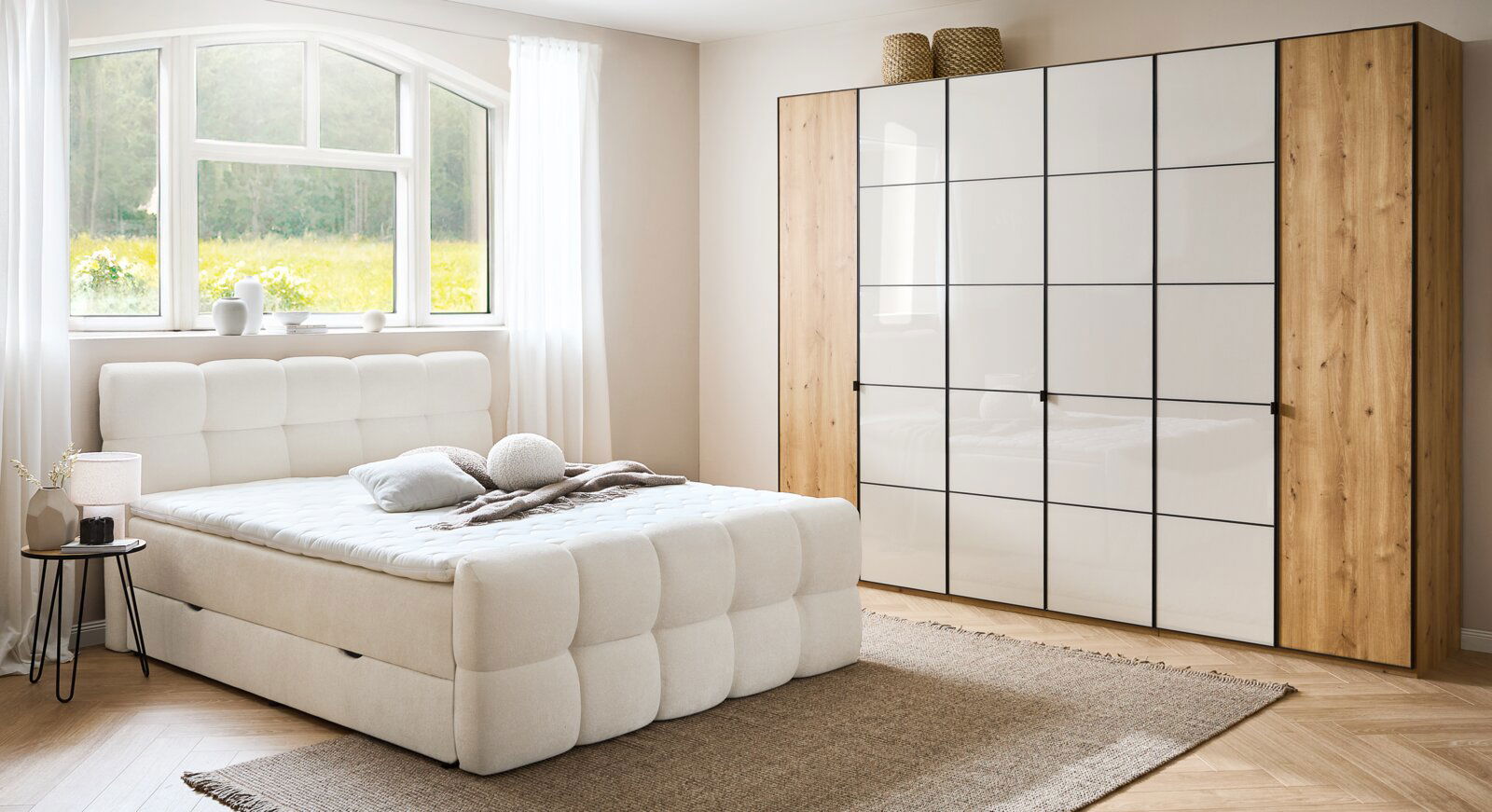 Gemütliches Boxbett in einem hellen Schlafzimmer mit großem Fenster, das Tageslicht hereinlässt. Perspektive von der Seite des Bettes.