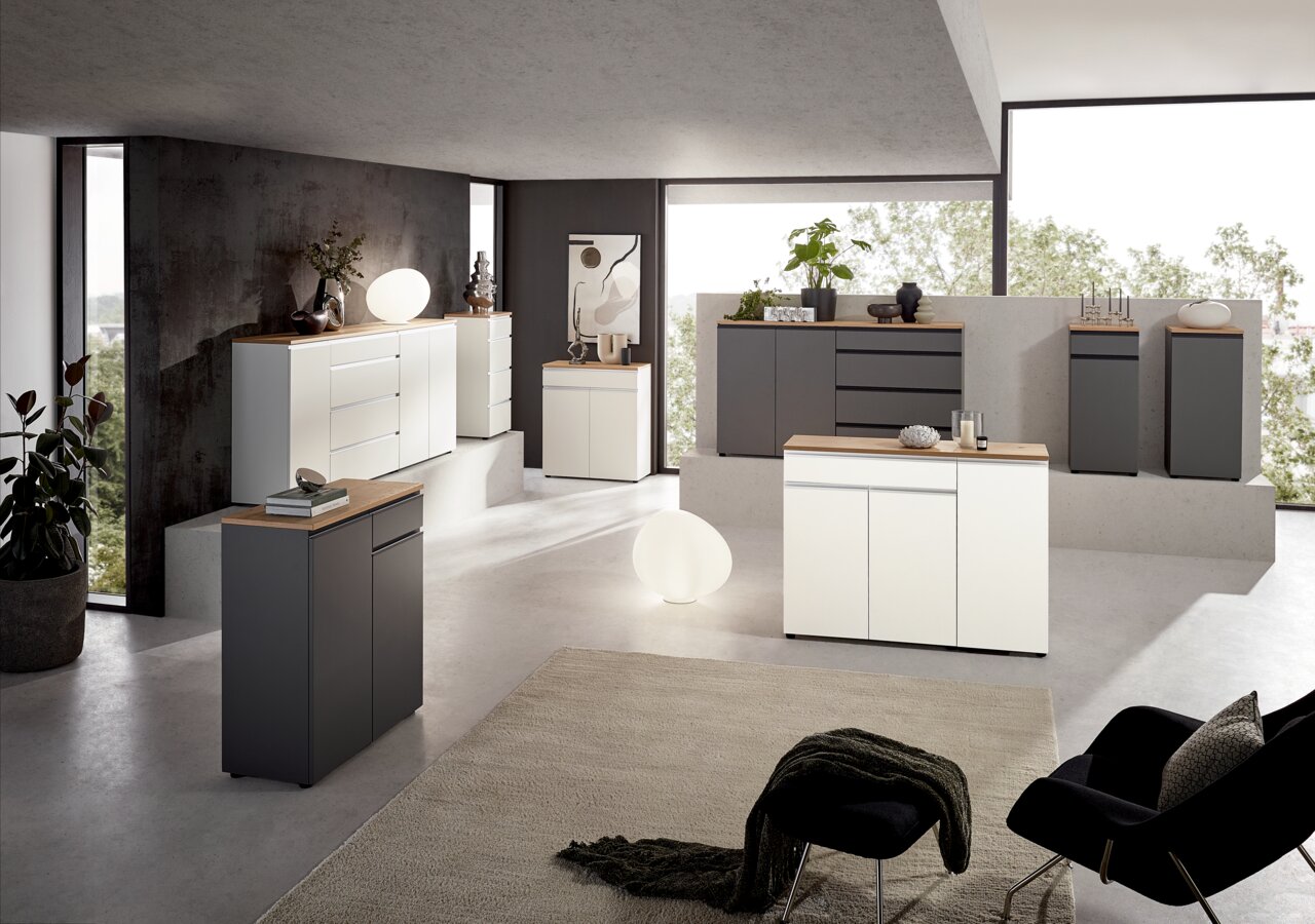 Dieter Knoll Kombi-Kommode LENDINA Moderne Wohnzimmereinrichtung mit verschiedenen Kommoden in Weiß und Grau, fotografiert aus einer leicht erhöhten Perspektive. Die Kommoden sind mit Dekorationsgegenständen wie Pflanzen und Lampen geschmückt.