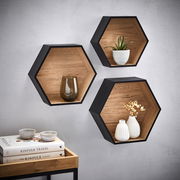 Dreiteiliges Wandregal-Set in Wabenform aus Holz mit schwarzem Rahmen, dekoriert mit Pflanzen und Vasen, seitliche Perspektive.