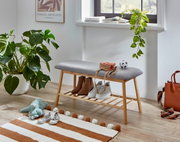 Gepolsterte Sitzbank mit grauem Stoffbezug und Holzgestell mit Schuhablage im Flur, seitliche Perspektive auf das Produkt
