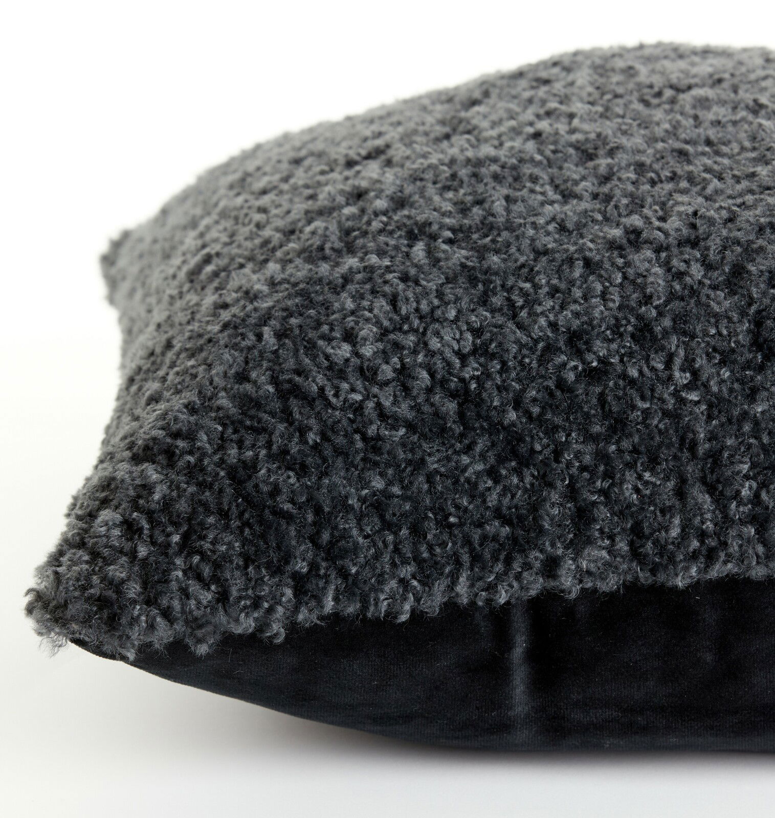 Nahaufnahme eines dunkelgrauen Kissens mit flauschiger Textur, seitliche Perspektive