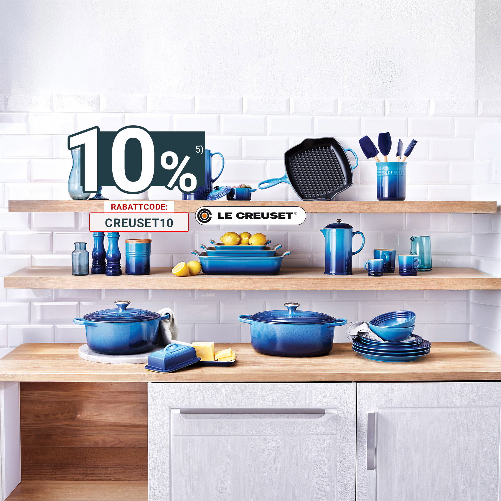 Le Creuset Küchenserie in Blau stilvoll auf offenen Holzregalen präsentiert