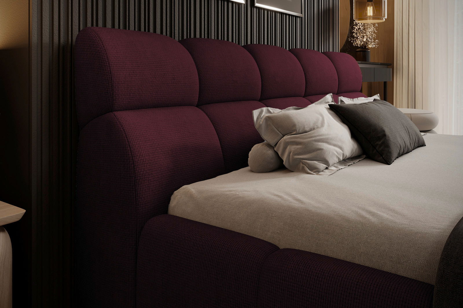 Seitliche Perspektive auf ein elegantes Polsterbettgestell in tiefem Burgunderrot mit weichen Kissen und einem modernen, stilvollen Design.