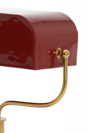 Nahaufnahme einer Tischleuchte mit rotem Lampenschirm und goldener Halterung, seitliche Perspektive