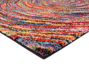 Bunte Nahaufnahme eines Hochflor-Teppichs mit spiralförmigem Muster, aus seitlicher Perspektive fotografiert.