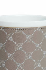 Nahaufnahme eines Porzellanbechers mit grauem, gemustertem Lederüberzug, von oben betrachtet.