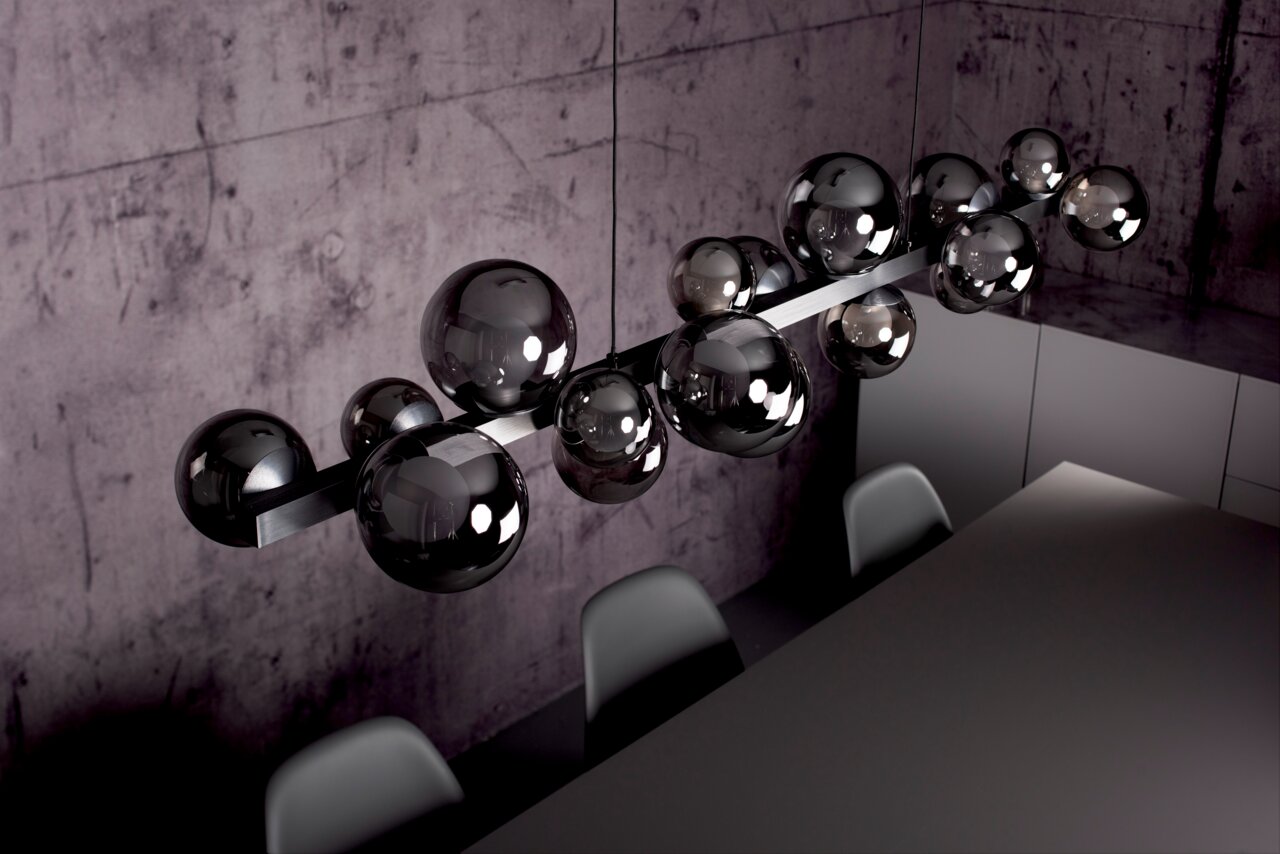 Moderne LED-Pendelleuchte mit mehreren glänzenden Kugeln, von oben fotografiert, über einem Esstisch in einem stilvollen Raum.
