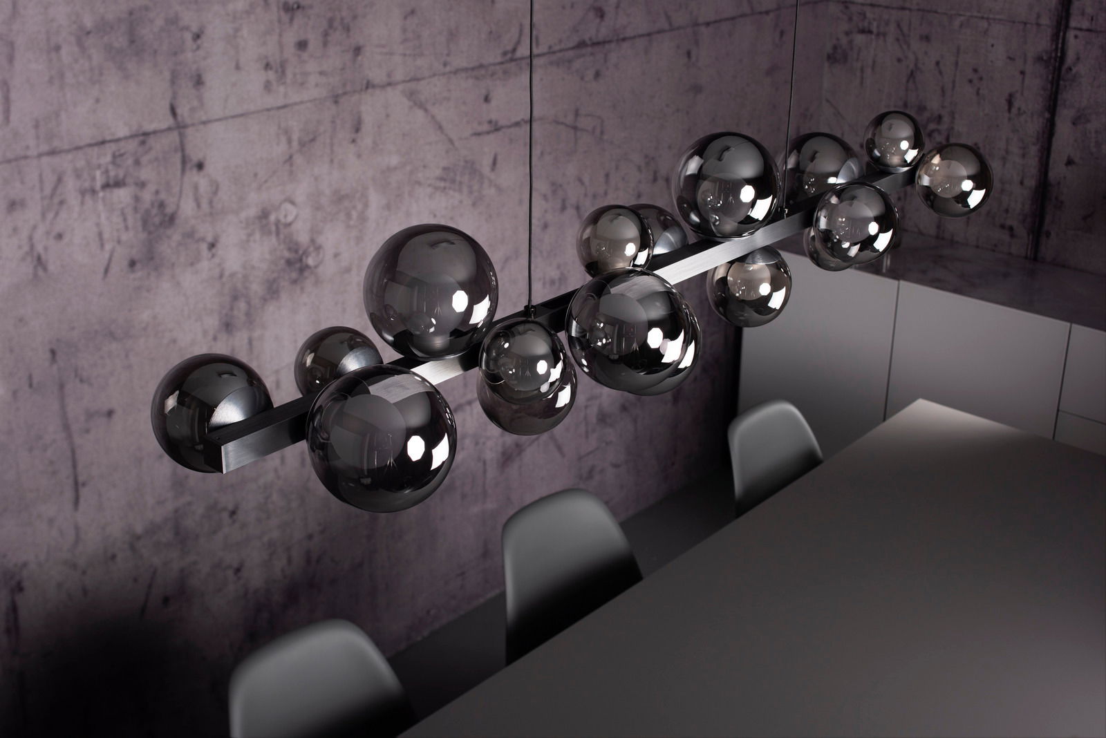 Moderne LED-Pendelleuchte mit mehreren glänzenden Kugeln, von oben fotografiert, über einem Esstisch in einem stilvollen Raum.