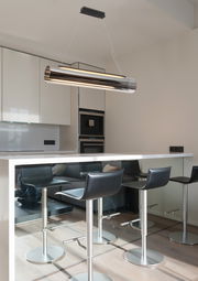 Moderne LED-Hängeleuchte in zylindrischer Form über einer Kücheninsel, seitliche Perspektive.