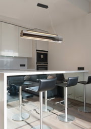 Moderne cilindervormige led-hanglamp boven een kookeiland, gezien vanaf de zijkant.