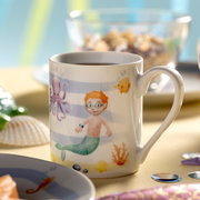 Tasse mit Meerjungfrauenmotiv, zeigt einen Jungen mit Brille als Meerjungmann, umgeben von einem Oktopus, Fischen und Korallen. Perspektive: seitlich.