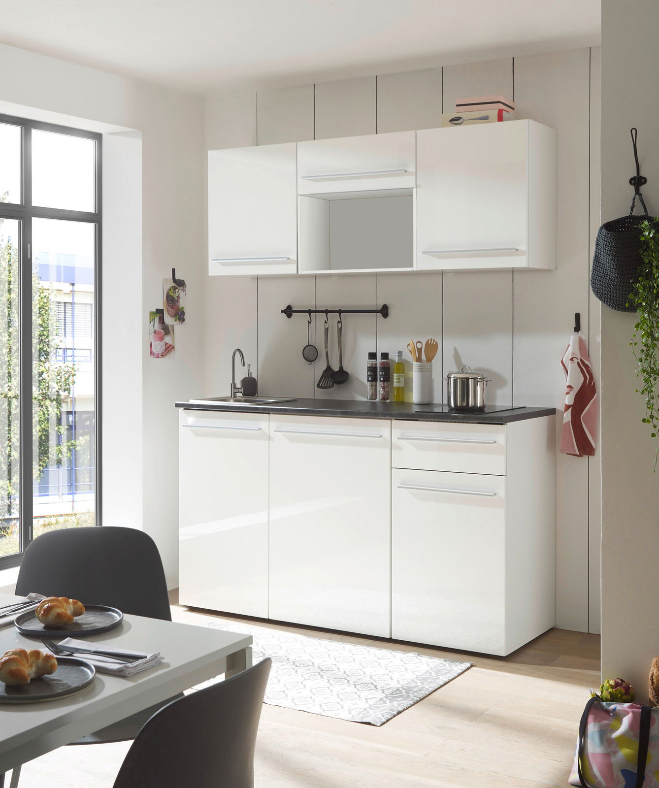 Moderne Single-Küche in Weiß mit Oberschränken, Spüle und Arbeitsfläche, seitliche Perspektive