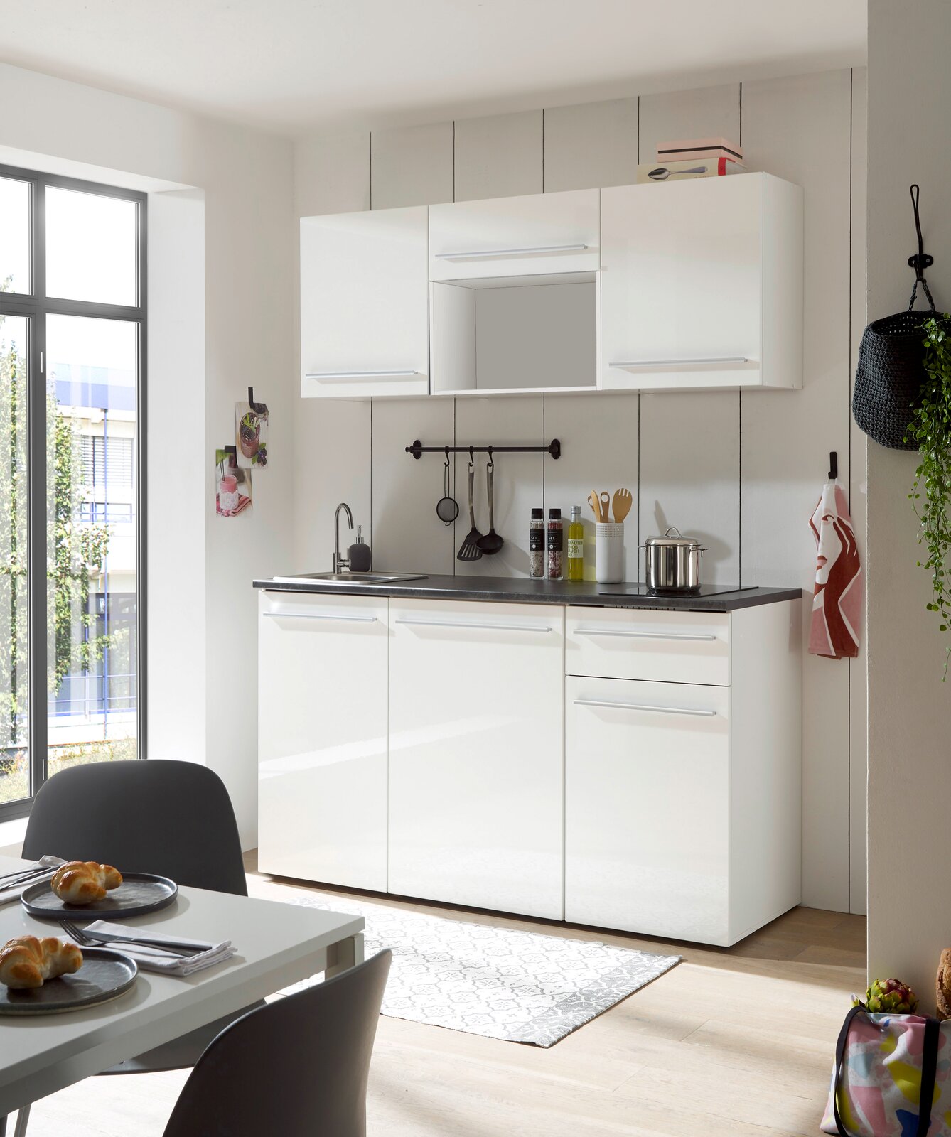 Moderne Single-Küche in Weiß mit Oberschränken, Spüle und Arbeitsfläche, seitliche Perspektive