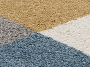 Nahaufnahme eines Uni-Teppichs mit geometrischem Muster in Blau, Grau, Beige und Weiß.